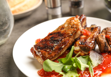 Delicious grilled ribs served on grey table, closeup