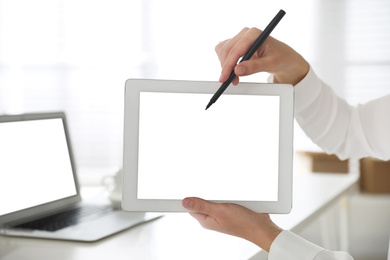 Photo of Woman pointing at modern tablet with blank screen in office, closeup