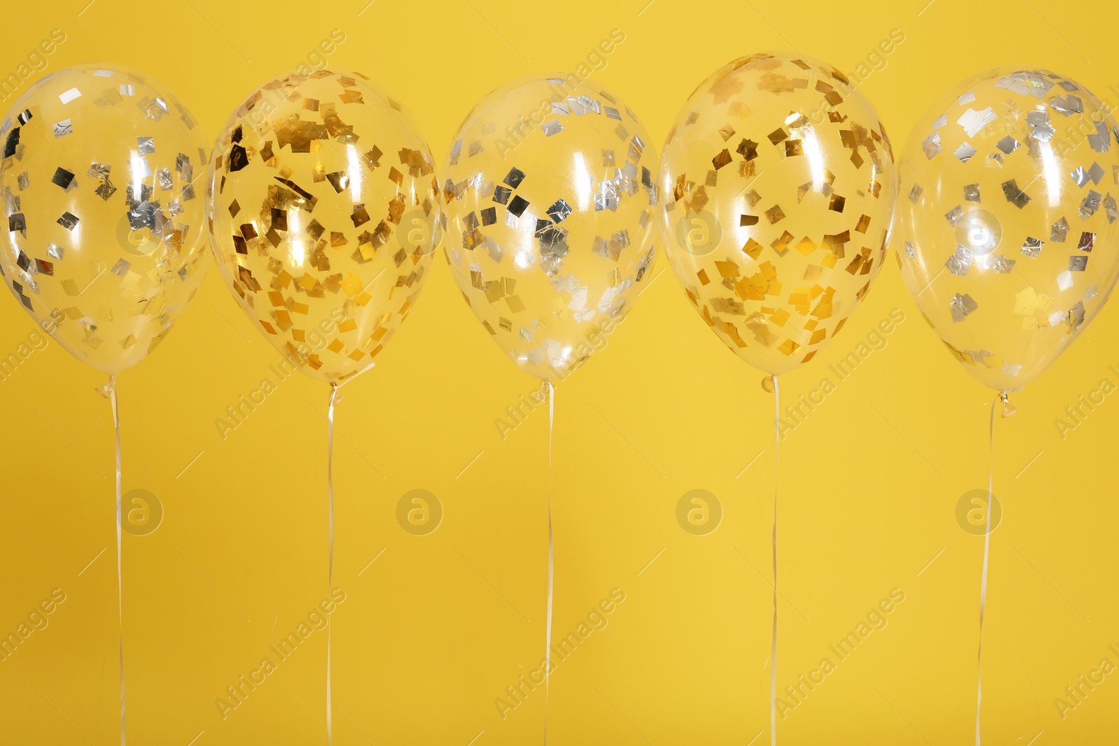 Photo of Bright balloons with ribbons on color background. Space for text