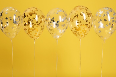 Photo of Bright balloons with ribbons on color background. Space for text