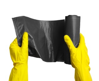 Photo of Person in rubber gloves holding roll of grey garbage bags on white background, closeup. Cleaning supplies