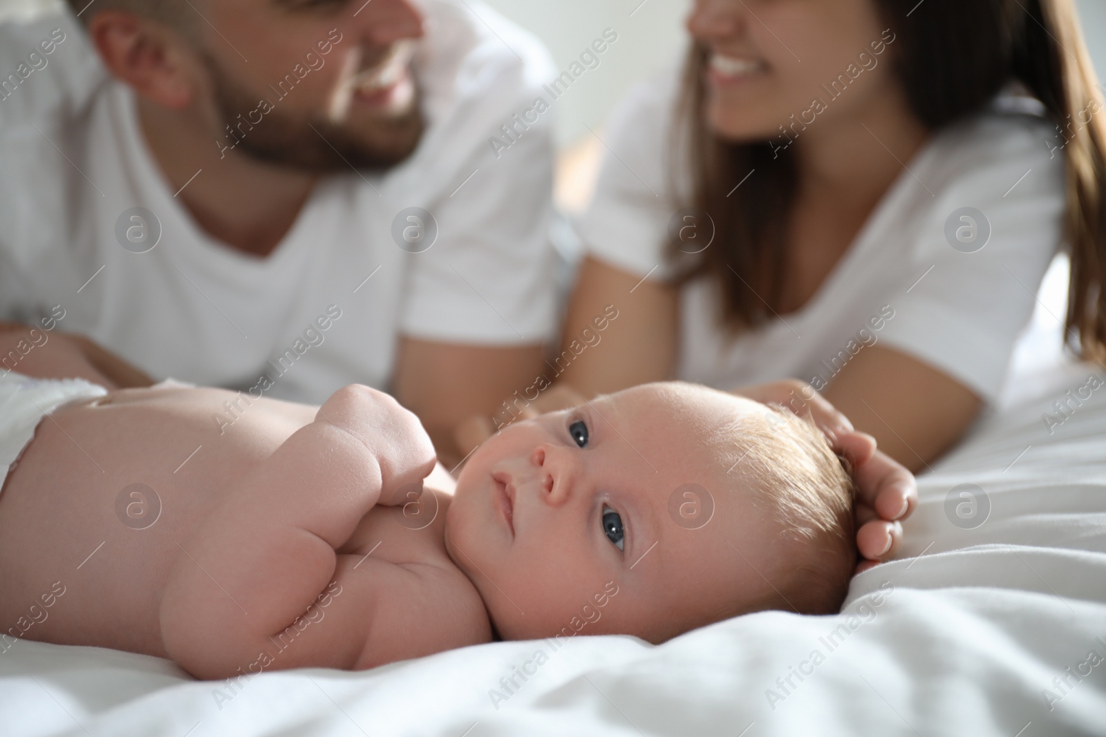 Photo of Newborn baby lying near parent on bed, closeup