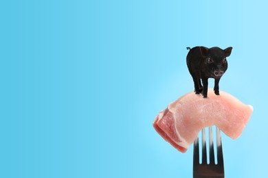 Image of Sample of lab grown pork and small pig on fork against light blue background, space for text. Cultured meat concept 