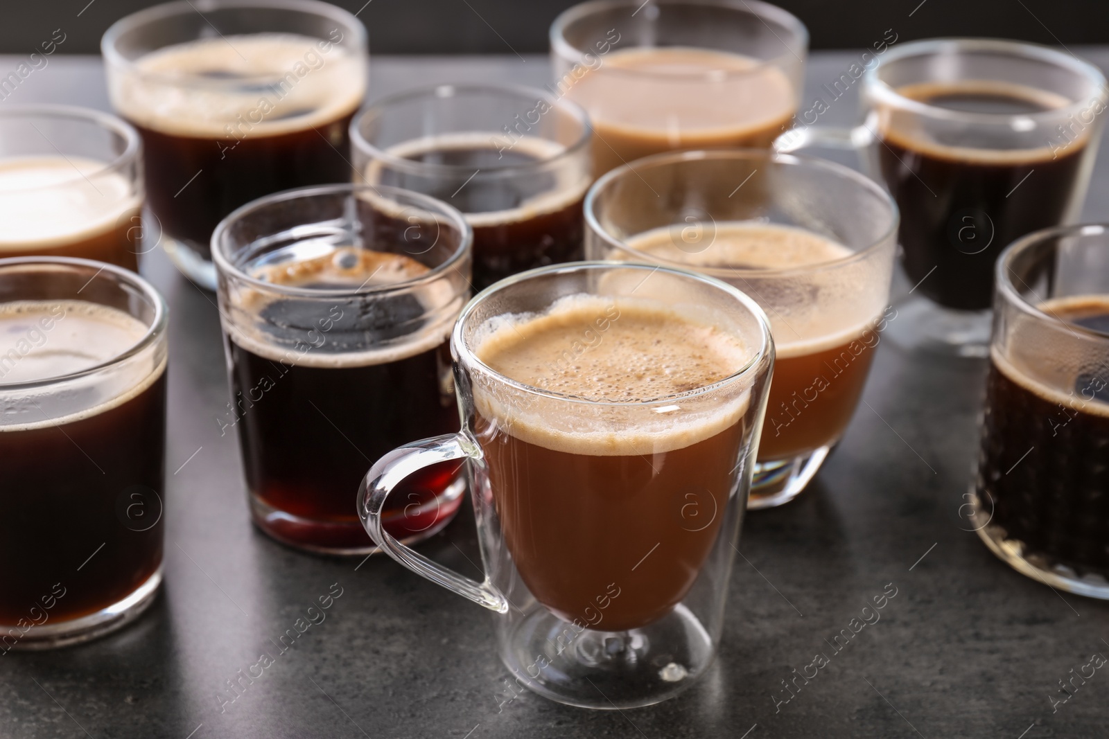 Photo of Many cups of different aromatic hot coffee on grey background