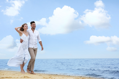 Happy couple having romantic walk on beach. Space for text