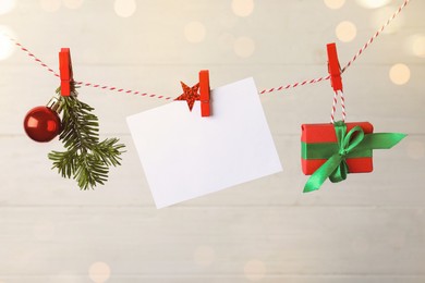 Blank Christmas card and festive decor on rope against white background, space for text