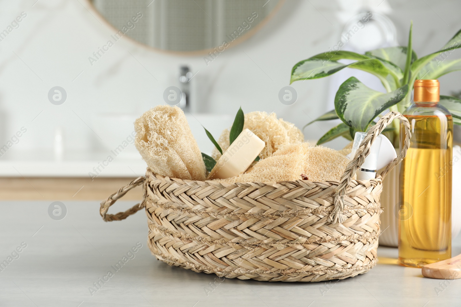 Photo of Natural loofah sponges and personal hygiene products on table in bathroom