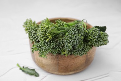 Bowl with fresh raw broccolini on white table, closeup. Healthy food