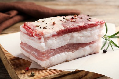 Photo of Tasty salt pork with rosemary and spices on wooden board, closeup