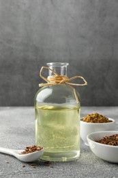 Photo of Caraway (Persian cumin) seeds, powder and essential oil on gray textured table, space for text