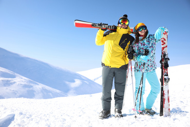 Photo of Young couple with skis on hill, space for text. Winter vacation