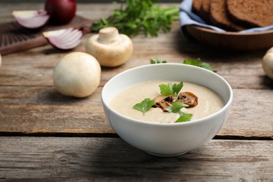 Photo of Bowl of fresh homemade mushroom soup on wooden table