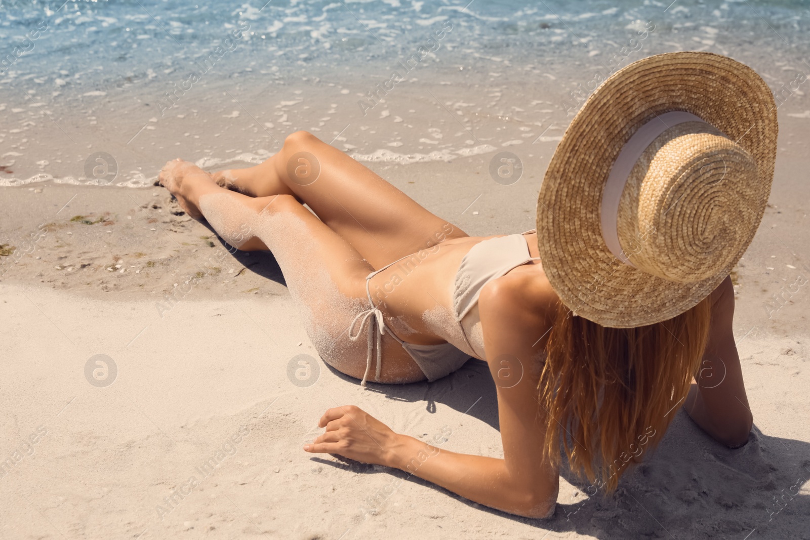 Photo of Woman in bikini on sandy beach near sea