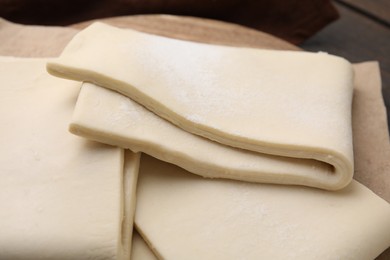 Photo of Raw puff pastry dough on table, closeup