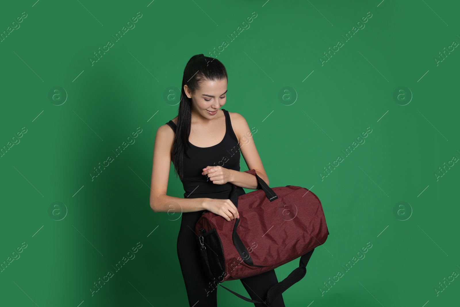 Photo of Beautiful woman with sports bag on green background