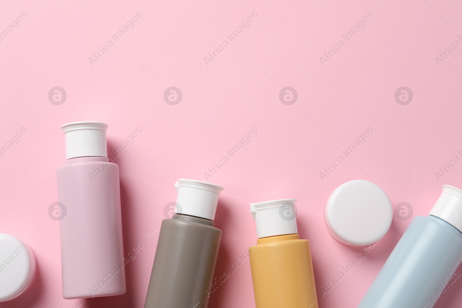 Photo of Cosmetic travel kit on pink background, flat lay. Space for text