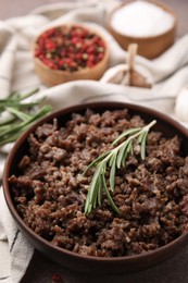 Photo of Fried ground meat in bowl and rosemary on table, closeup