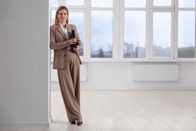 Photo of Happy real estate agent with leather portfolio in new apartment