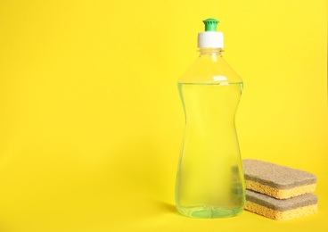 Cleaning product and sponges on yellow background, space for text. Dish washing supplies