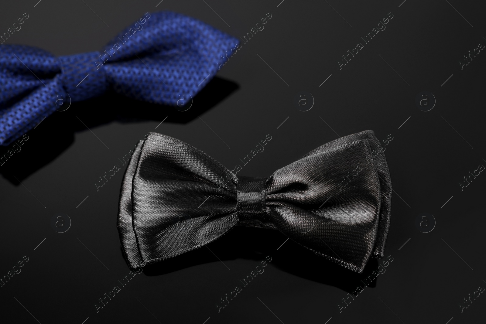 Photo of Stylish black bow tie on dark surface