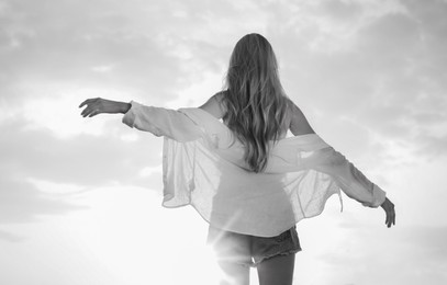 Young woman outdoors at sunset, back view. Black and white effect