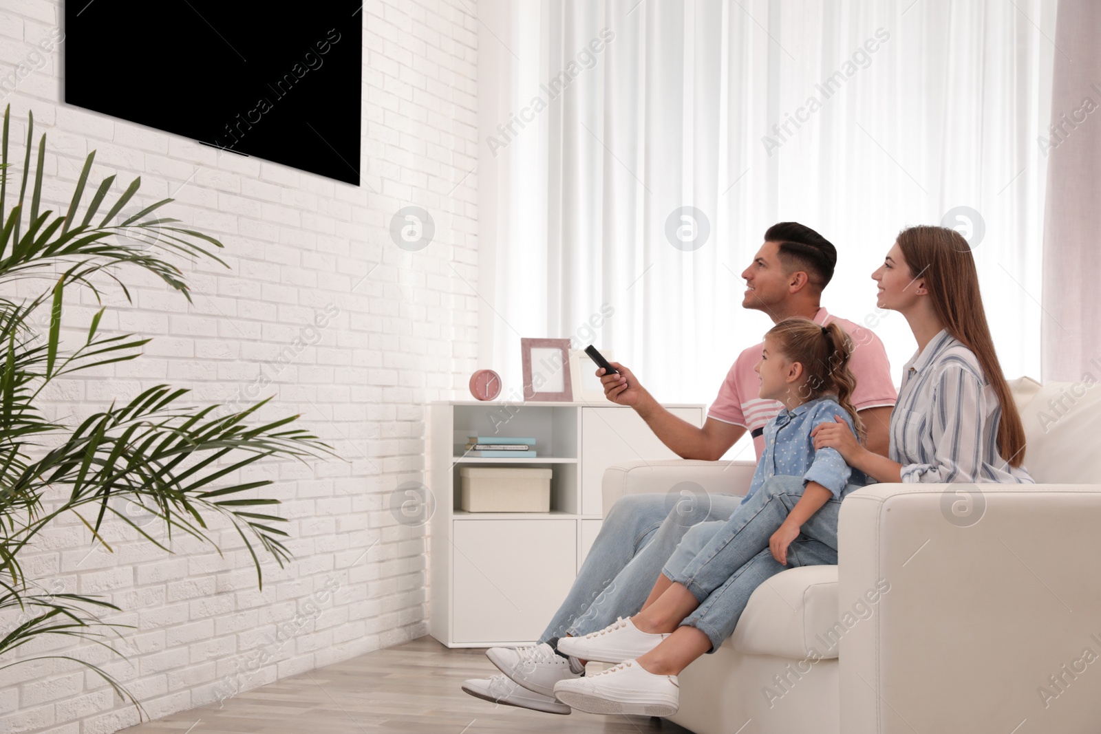 Photo of Happy family watching TV on sofa at home