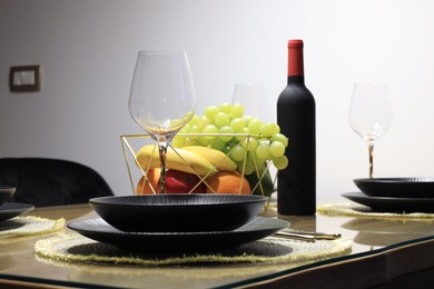 Photo of Bottle of wine, plates, fresh fruits and glasses on table