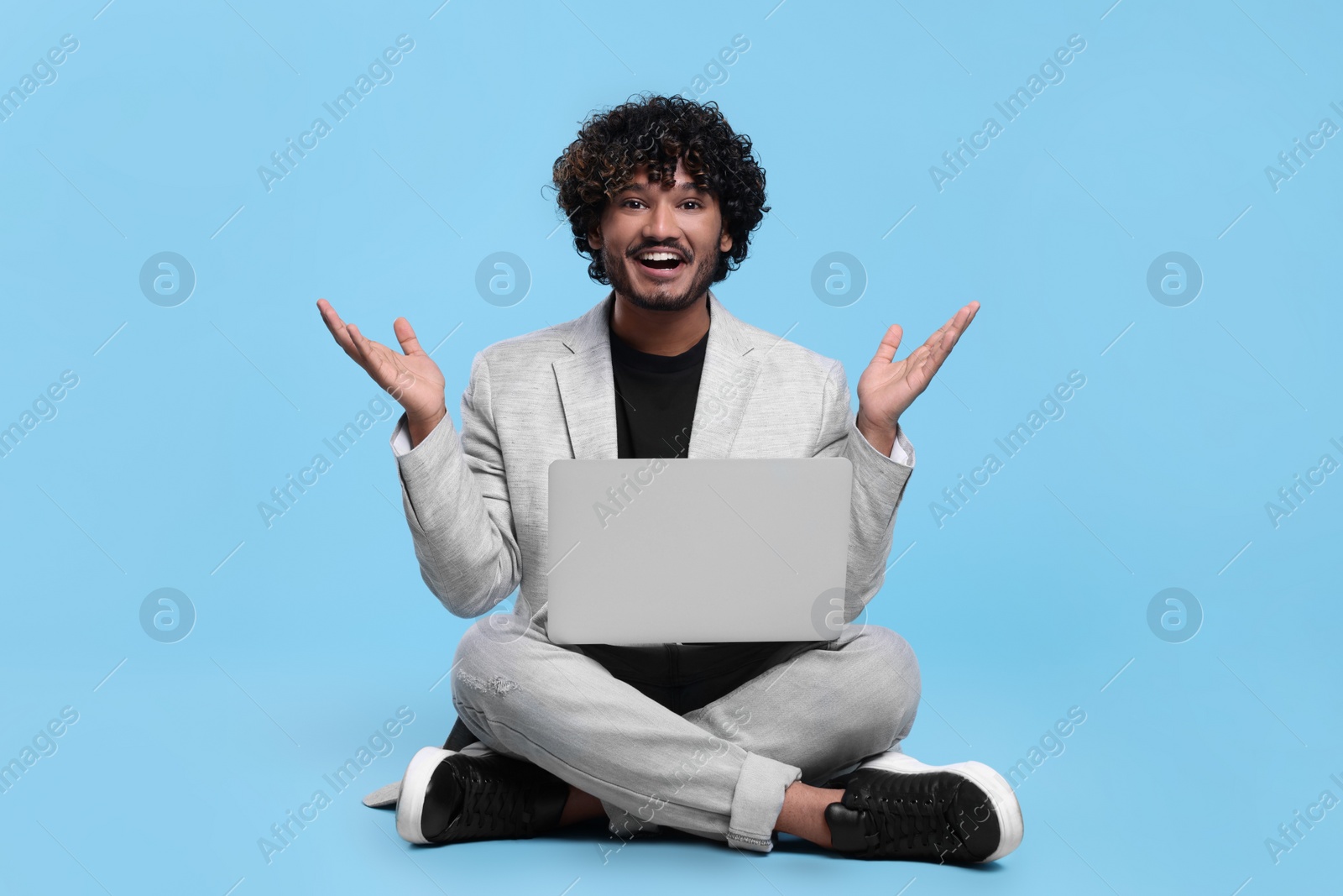 Photo of Smiling man with laptop on light blue background. Space for text