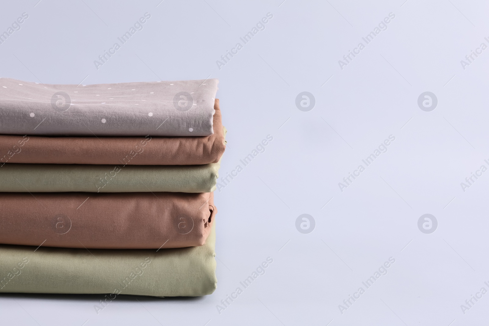 Photo of Stack of clean bed sheets on white background. Space for text