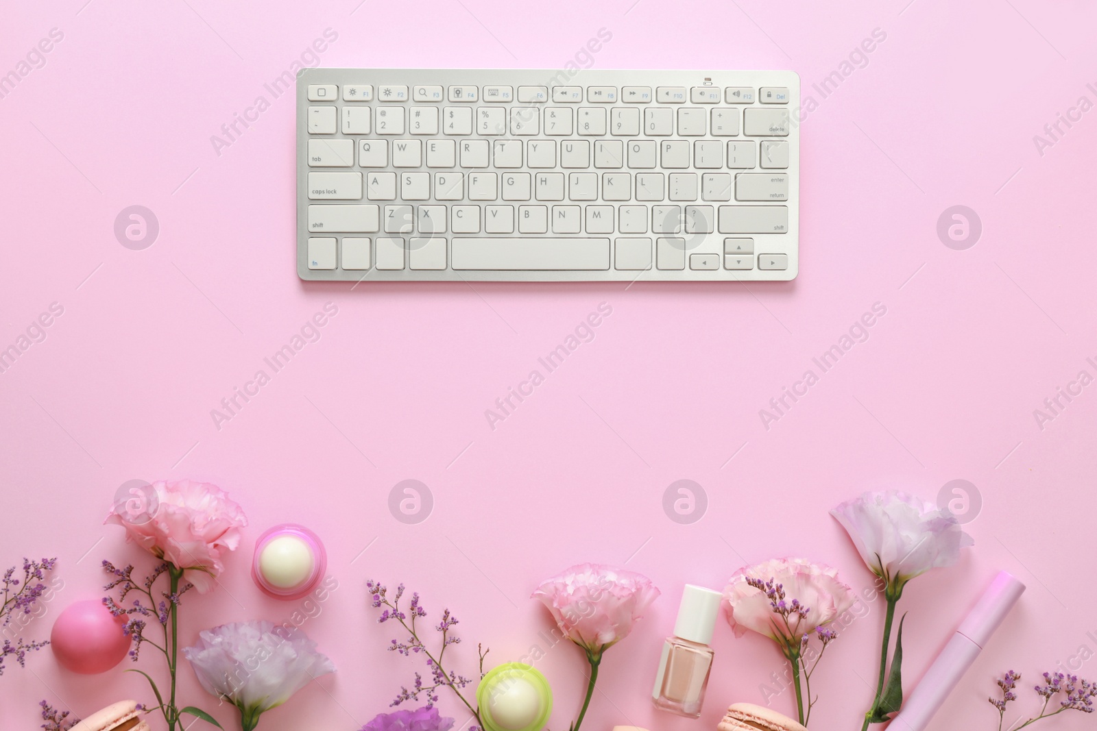 Photo of Flat lay composition with keyboard and flowers on pink background. Beauty blogger's workplace