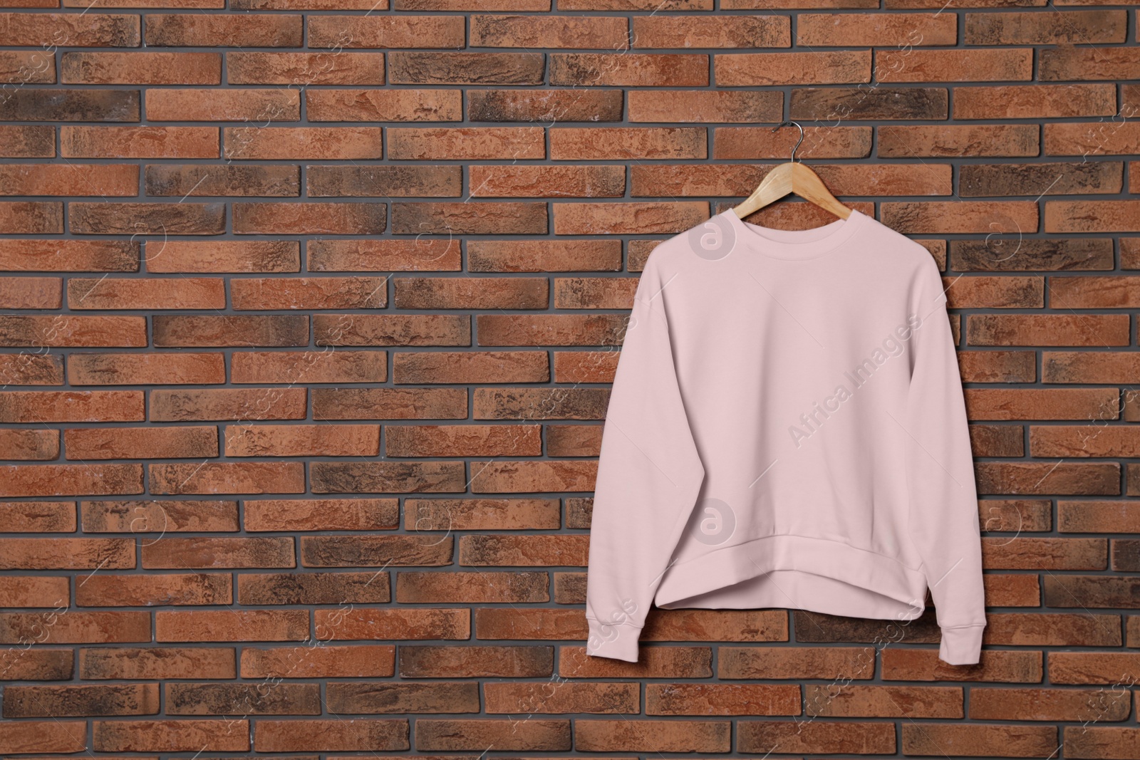 Photo of Hanger with new female sweater on brick wall, mock up for design