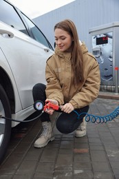 Young woman inflating tire at car service