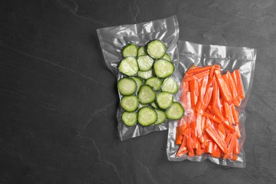 Photo of Sliced vegetables in vacuum packings on dark grey table, flat lay. Space for text