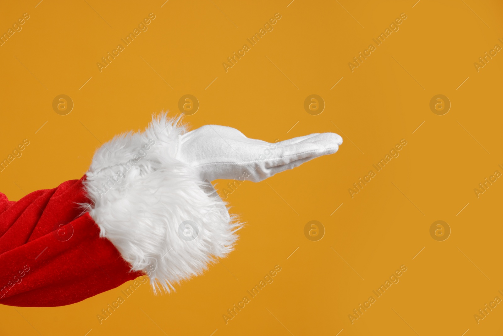Photo of Merry Christmas. Santa Claus holding something on orange background, closeup