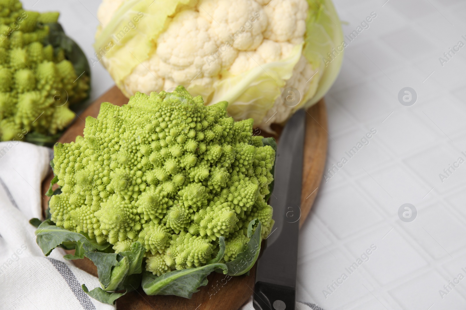 Photo of Fresh Romanesco broccoli and cauliflower on white tiled table, closeup. Space for text