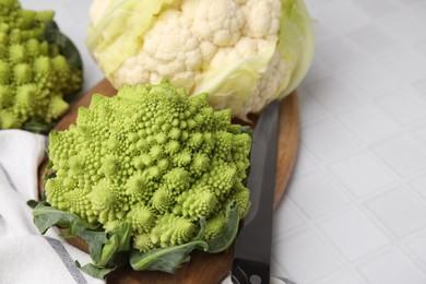 Fresh Romanesco broccoli and cauliflower on white tiled table, closeup. Space for text