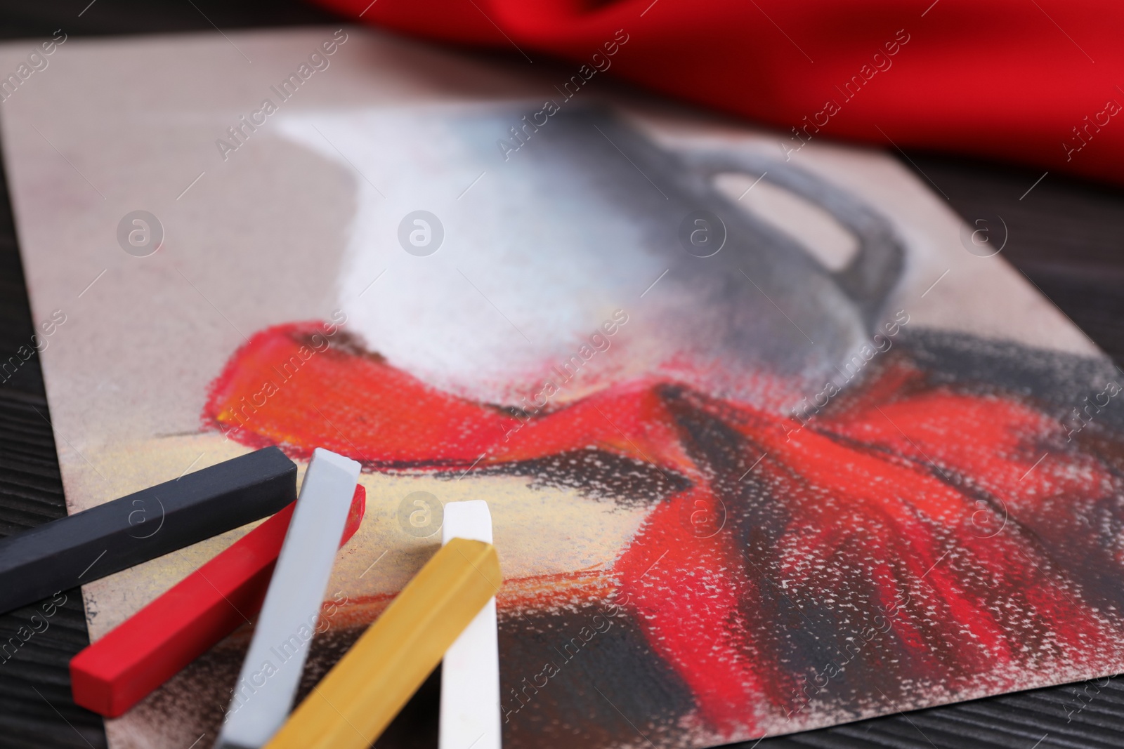 Photo of Colorful chalk pastels and beautiful painting of jug on black wooden table, closeup