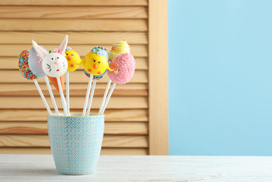 Photo of Different delicious sweet cake pops on white wooden table, space for text. Easter holiday