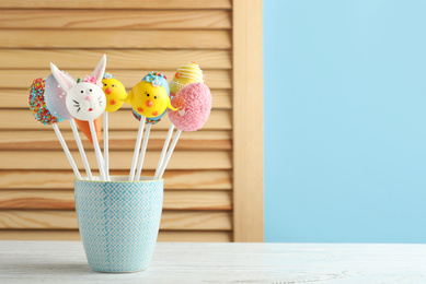 Different delicious sweet cake pops on white wooden table, space for text. Easter holiday