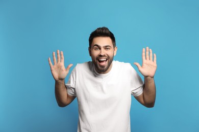 Young man laughing on light blue background. Funny joke