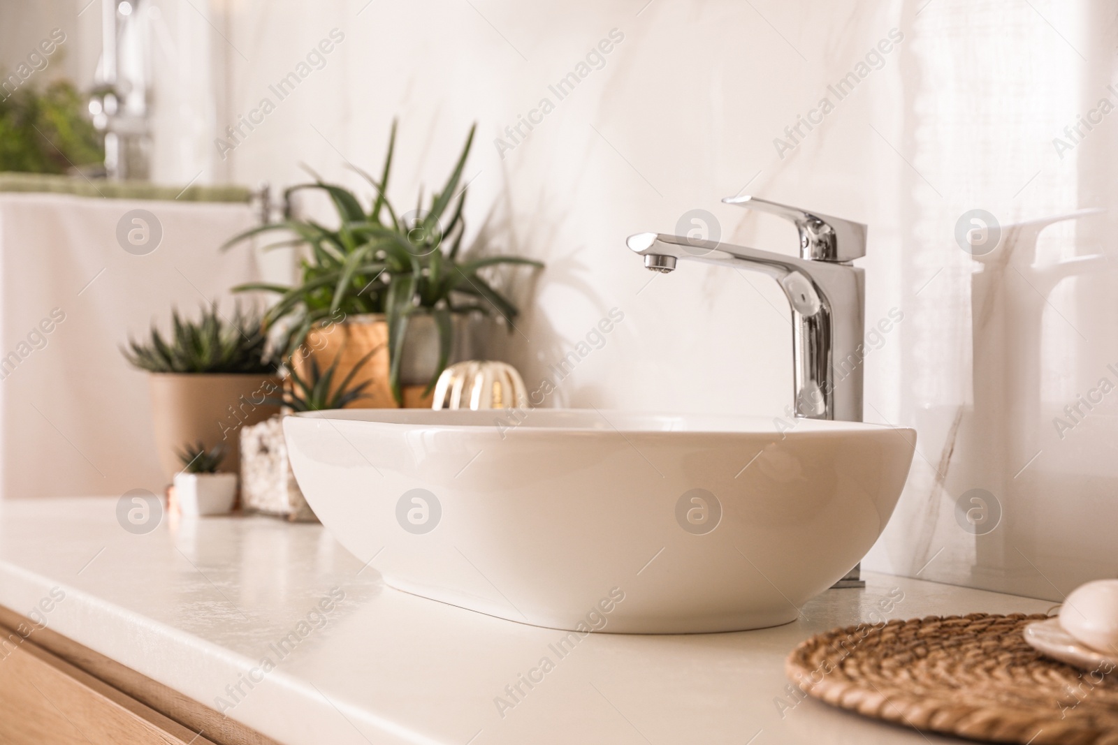 Photo of Countertop with sink and houseplants in bathroom. Interior design