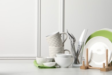 Photo of Beautiful ceramic dishware, cups and cutlery on white marble table, space for text