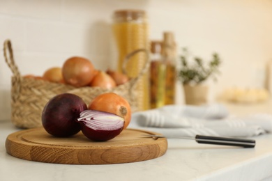 Photo of Fresh cut and whole onions on countertop in modern kitchen, closeup