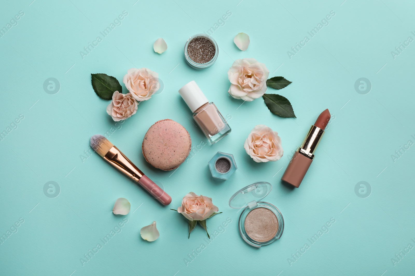 Photo of Flat lay composition with makeup products, roses and macaron on turquoise background