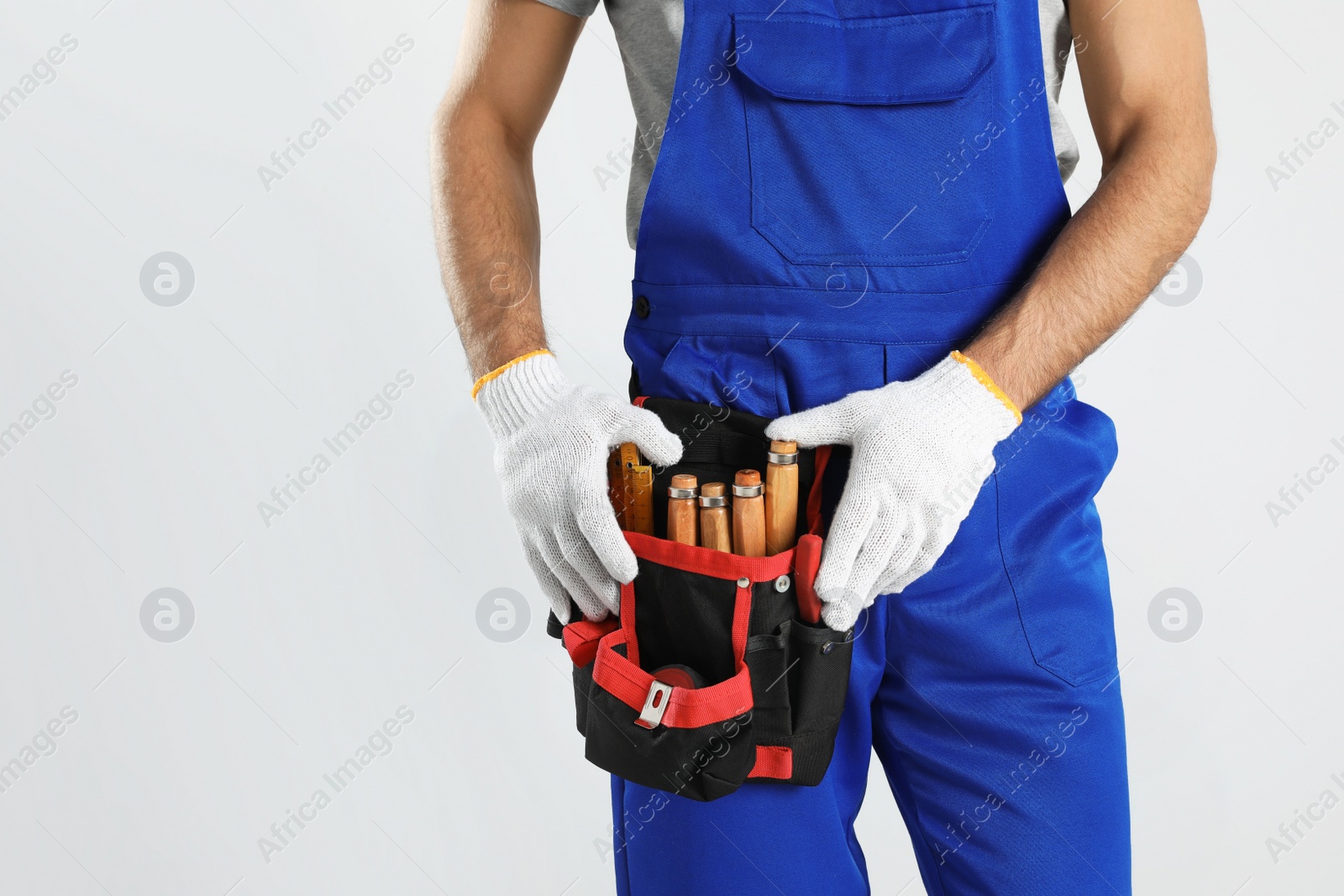 Photo of Carpenter with tool belt on light background, closeup