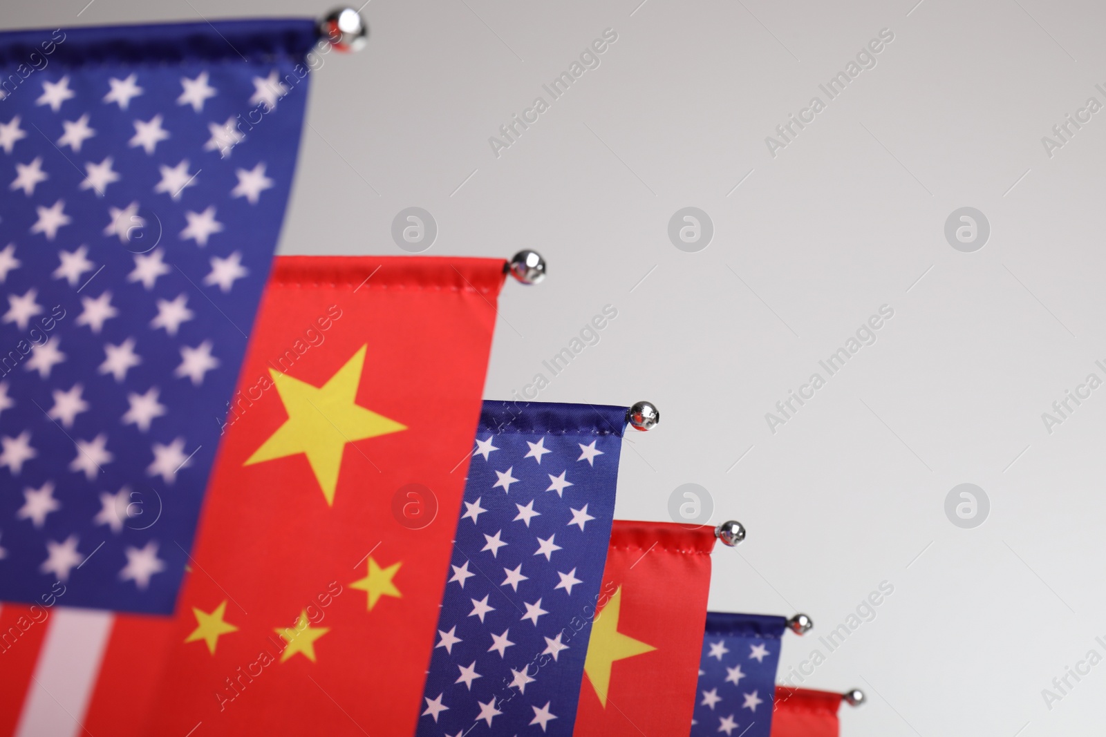 Photo of USA and China flags on light background, closeup. International relations