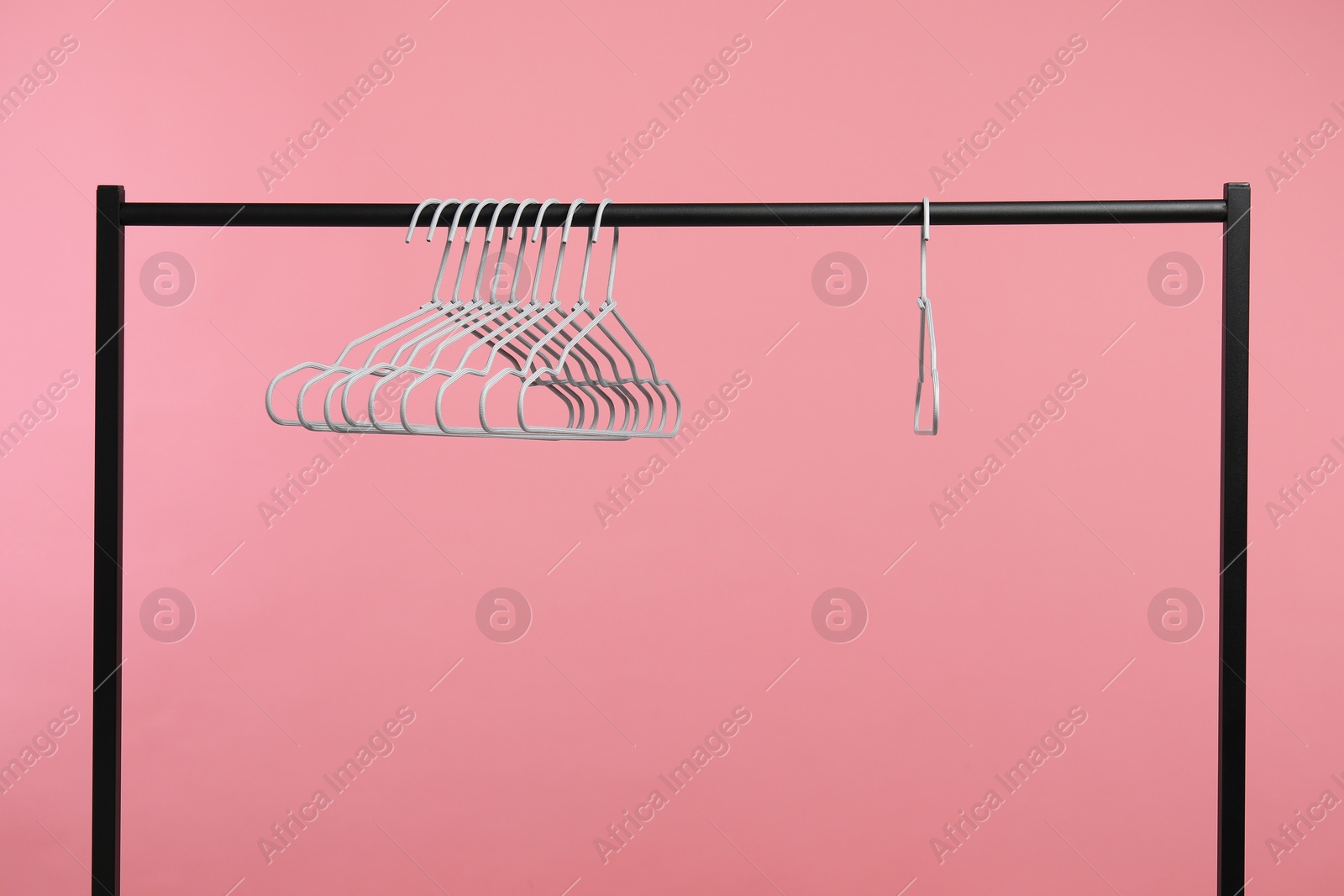 Photo of Empty clothes hangers on rack against pink background