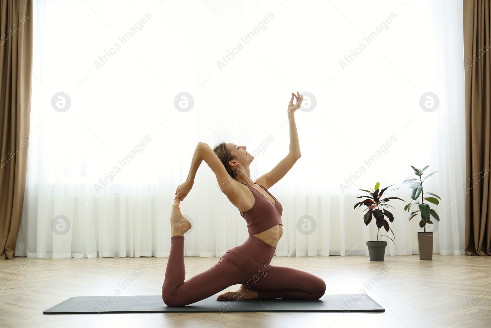 Photo of Young woman practicing one legged king pigeon asana in yoga studio. Eka pada rajakapotasana pose