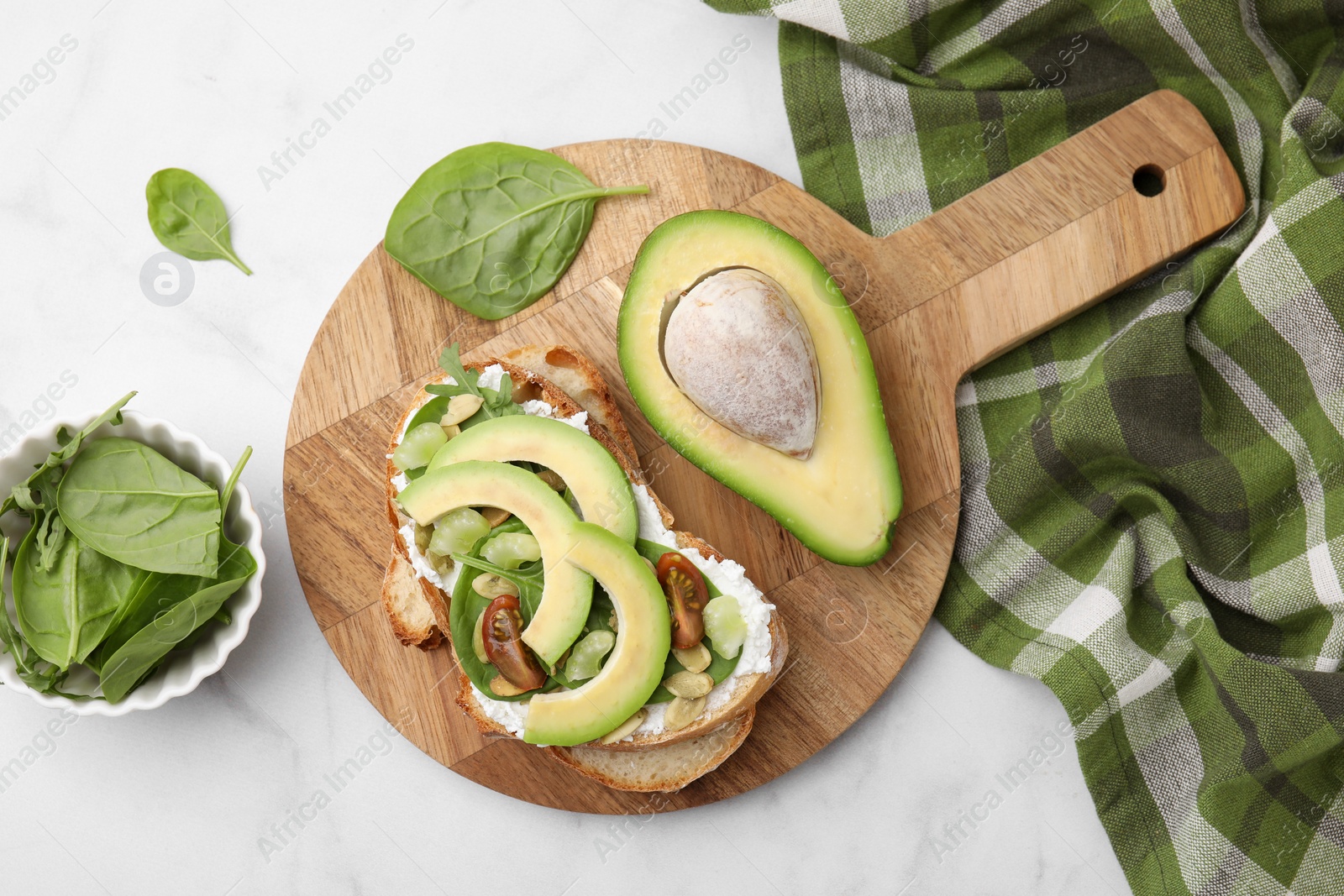 Photo of Tasty vegan sandwich with avocado, tomato and spinach on white marble table, flat lay