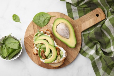 Tasty vegan sandwich with avocado, tomato and spinach on white marble table, flat lay